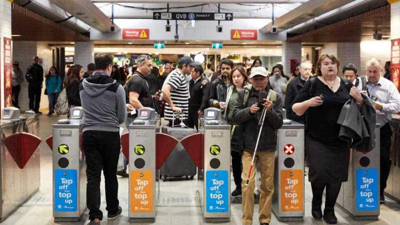 Commuters pass through barriers at a train station.