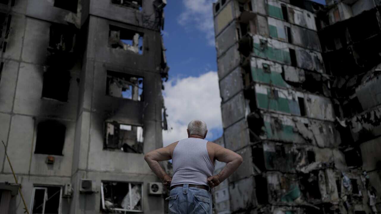 A man stands looking at a building destroyed by missile attacks