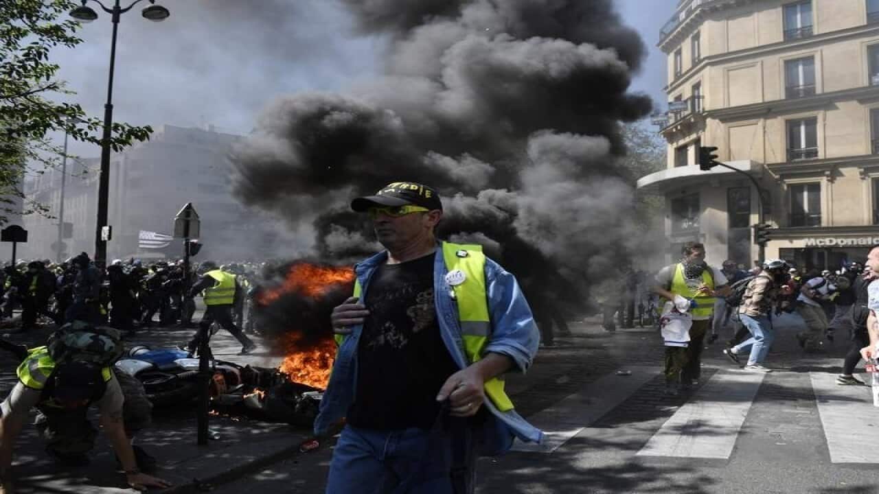Protesters run from the police after setting a street fire