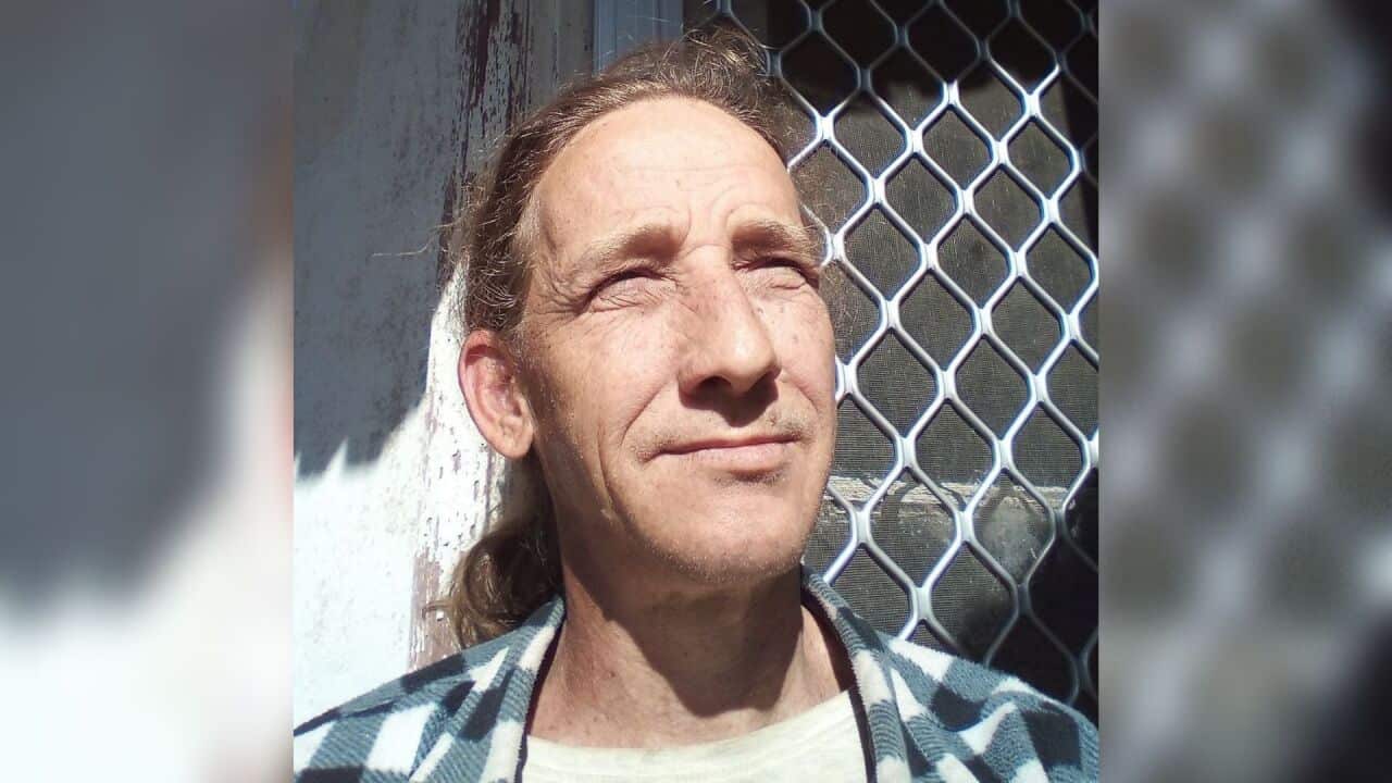 A man in a flannel and long hair.