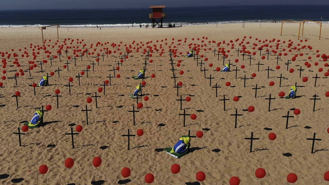 Crosses and red balloons are placed in the sand on Copacabana beach in a demonstration organized by Rio de Paz to honor the victims of COVID-19.
