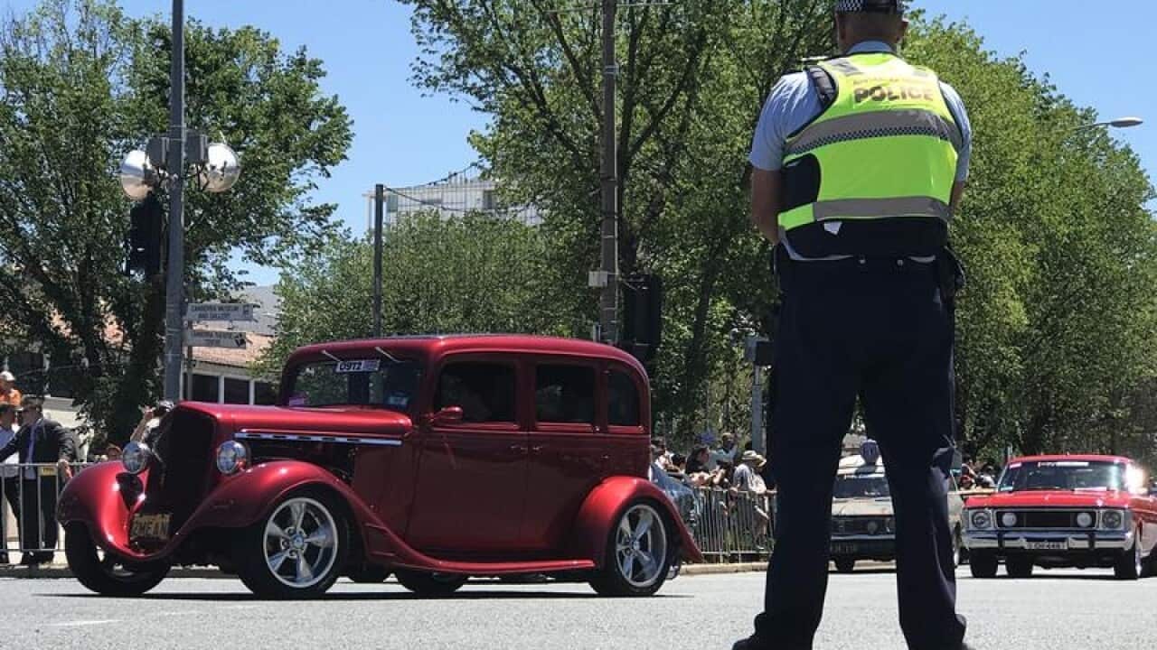 Classic cars drive down Canberra' main street.