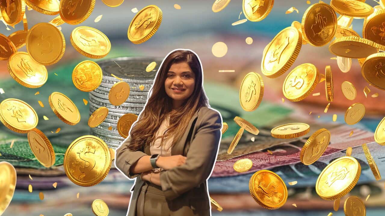 Indian-origin Australian tax agent Deepika Sharma smiling in front of stacked coins and paper currency, surrounded by falling gold coins, symbolising wealth, savings, investment, or financial prosperity.