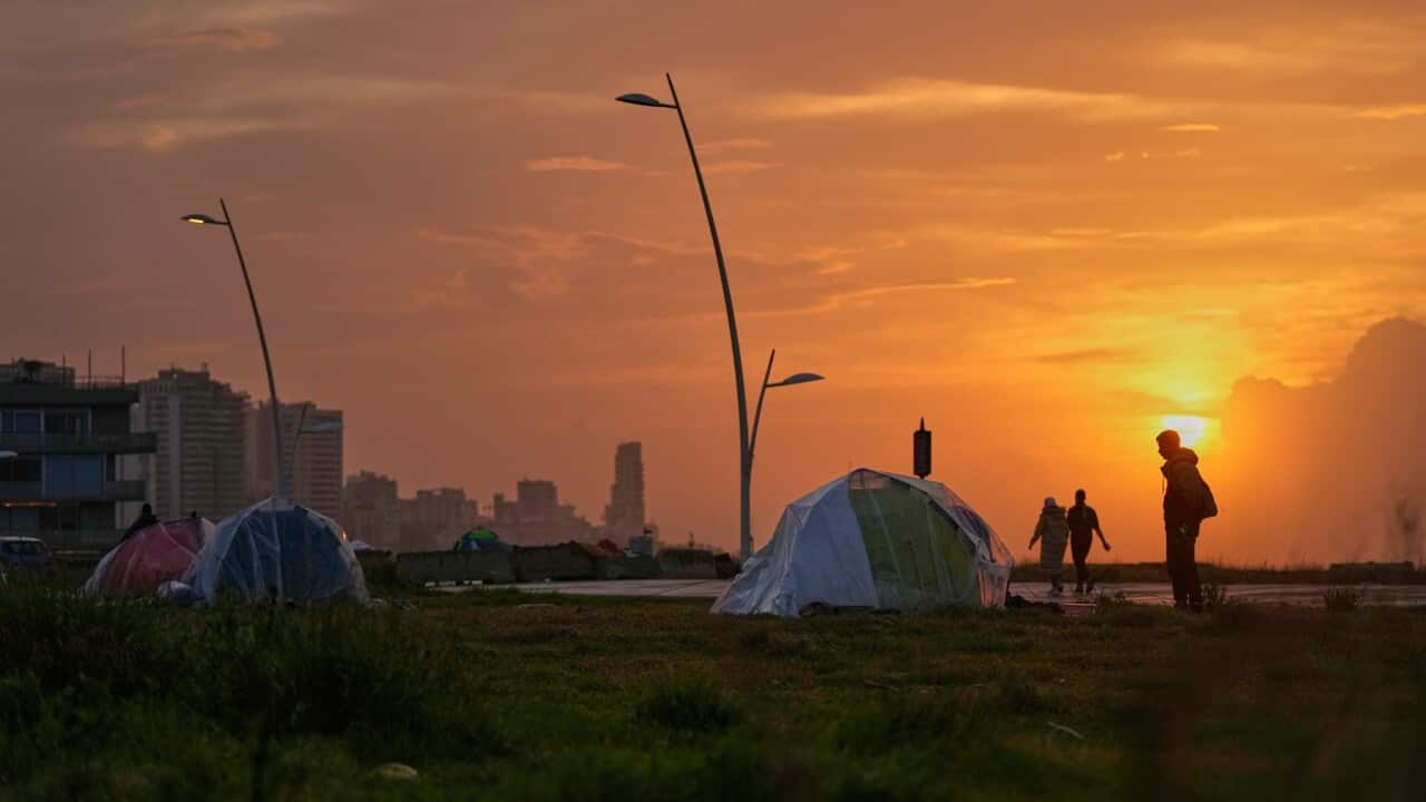People in Beirut walk past tents sheltering people displaced by Israeli airstrikes