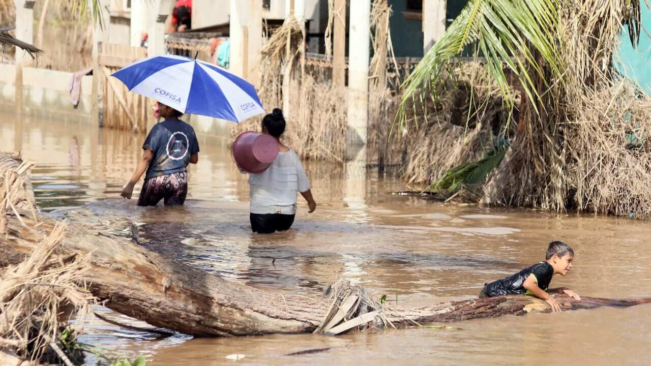 People affected by storms Eta and Iota navigate a flooded street in La Guadalupe, Honduras, on 30 November.
