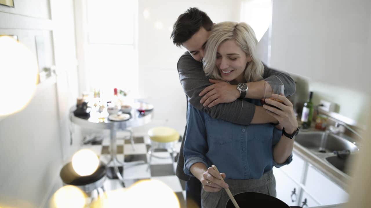Affectionate young couple hugging, cooking in apartment kitchen