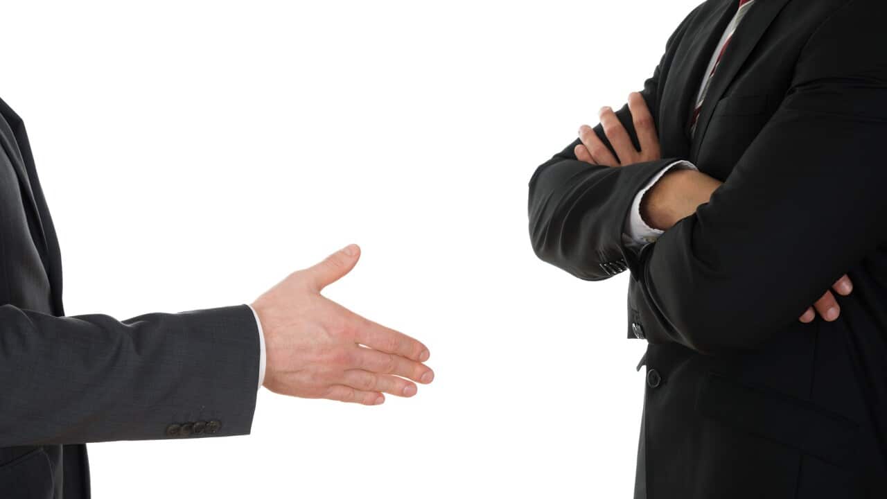 Person Offering Handshake To Man With Arms Crossed