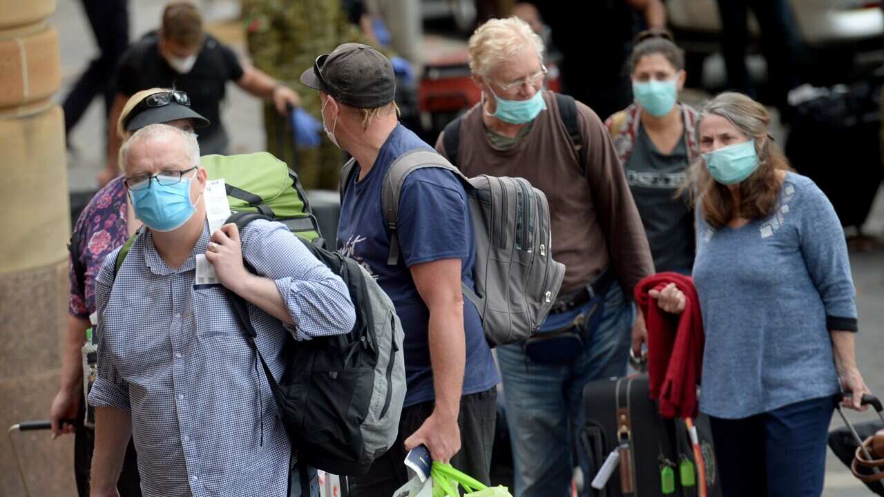 Returning overseas travellers are ushered into the InterContinental Hotel for the beginning of their 14-day imposed quarantine in Sydney, Sunday, March 29, 2020. (AAP Image/Jeremy Piper) NO ARCHIVING