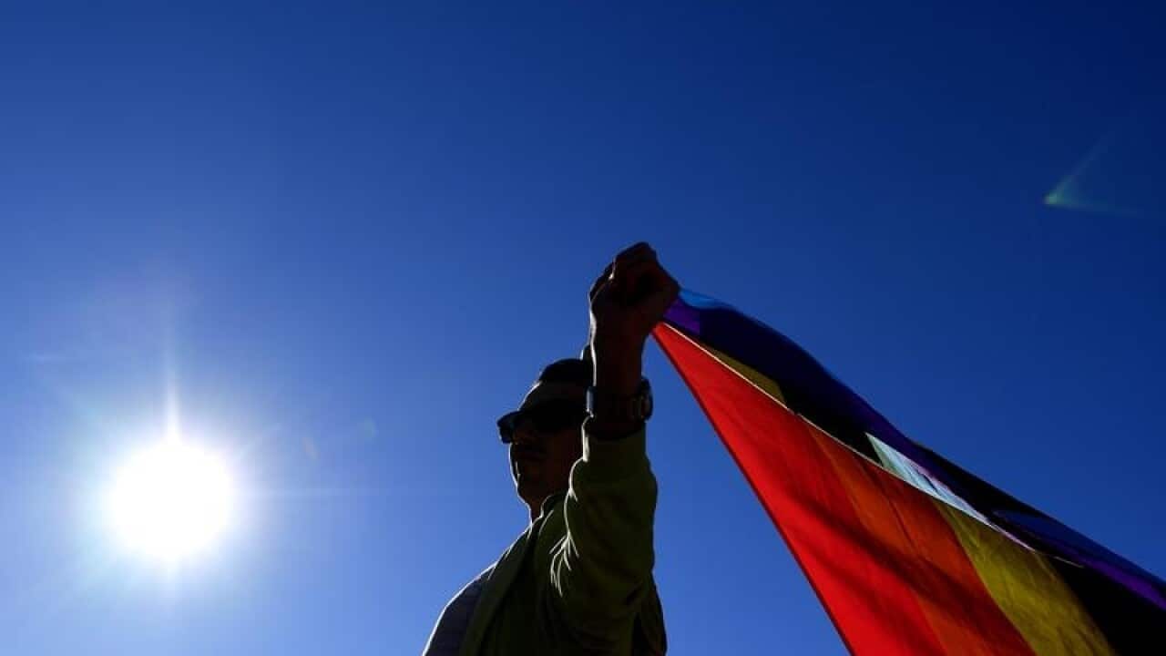 A marriage equality advocate holds a rainbow flag