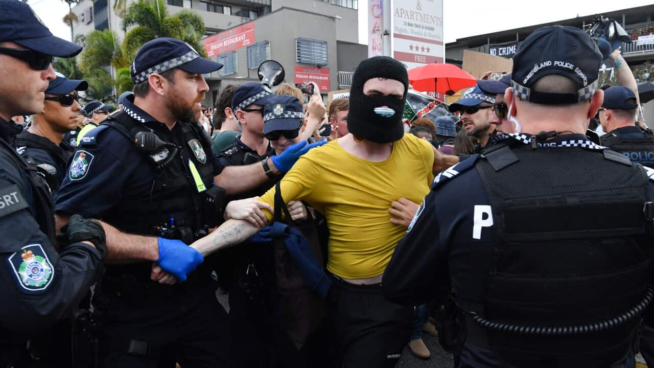 A protester (centre) is seen being detained by police during a rally in support of asylum seekers detained at the Kangaroo Point Central Hotel in Brisbane