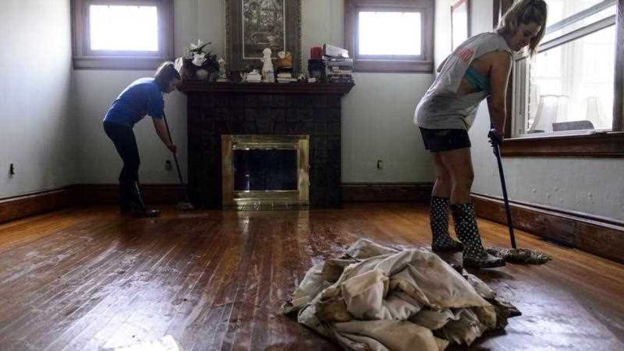 Rikki Spinks, left, and Crystal Evans mop the floors of Bob and Janice Evan's house in Clendenin, W.Va.