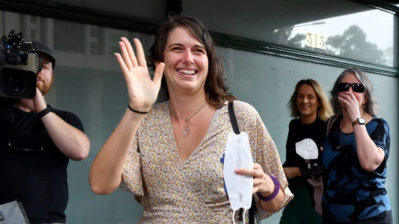 A woman waves to supporters outside the court.
