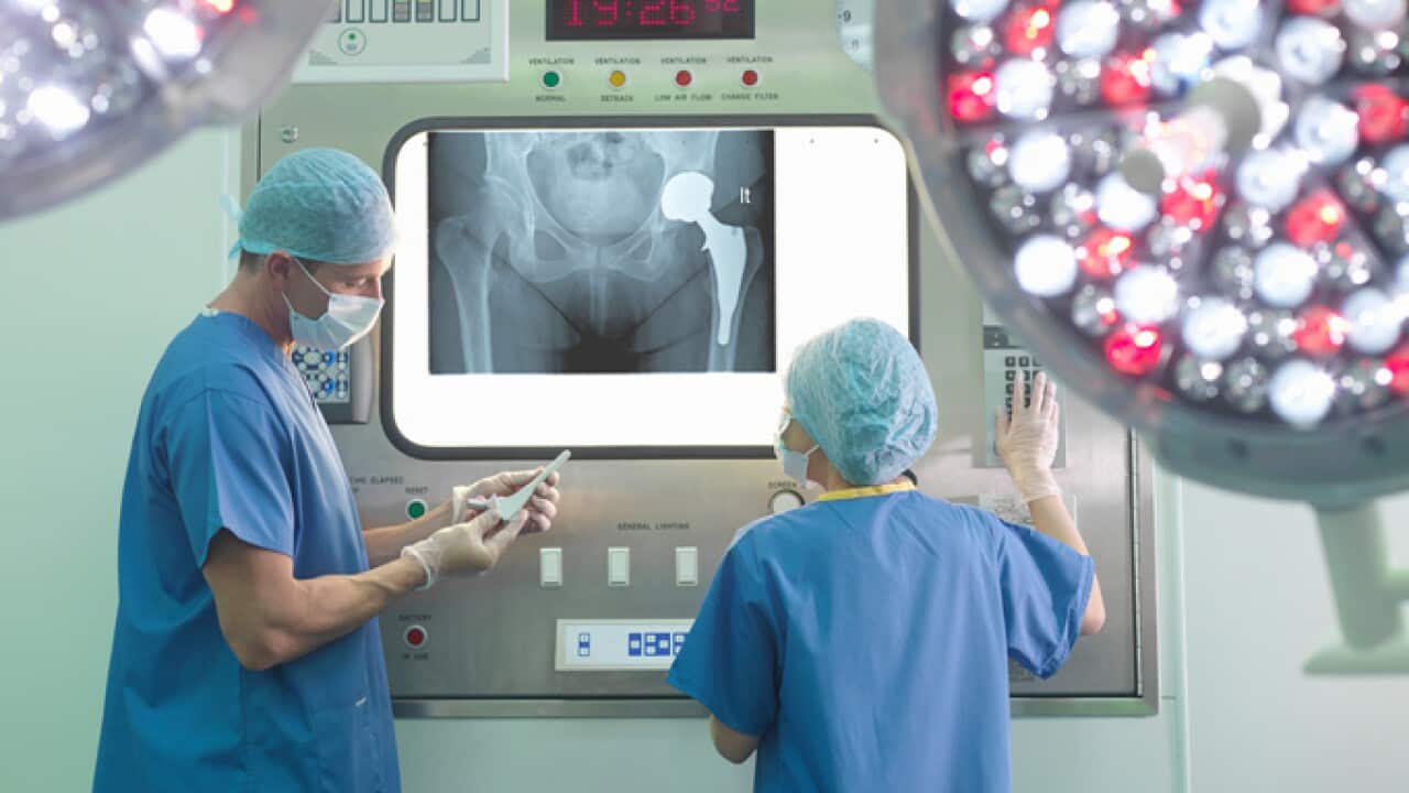 Orthopaedic surgeon and nurse with replacement hip stem in operating theatre