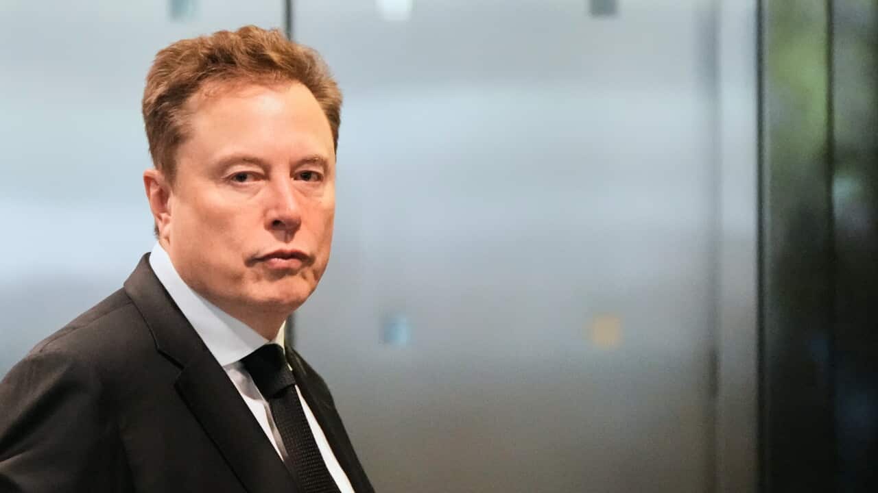 A middle aged man with short hair. He is dressed in a dark suit