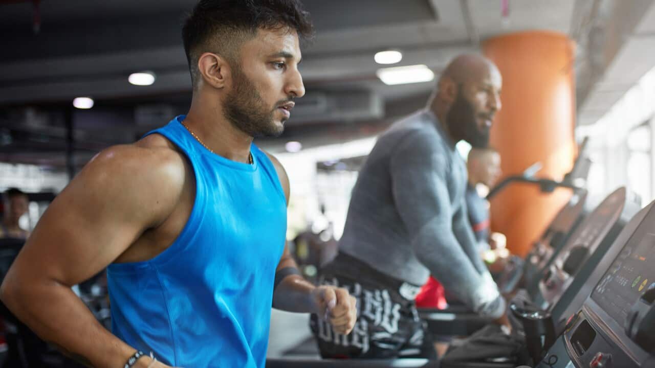 Determined mature man running on treadmill in gym