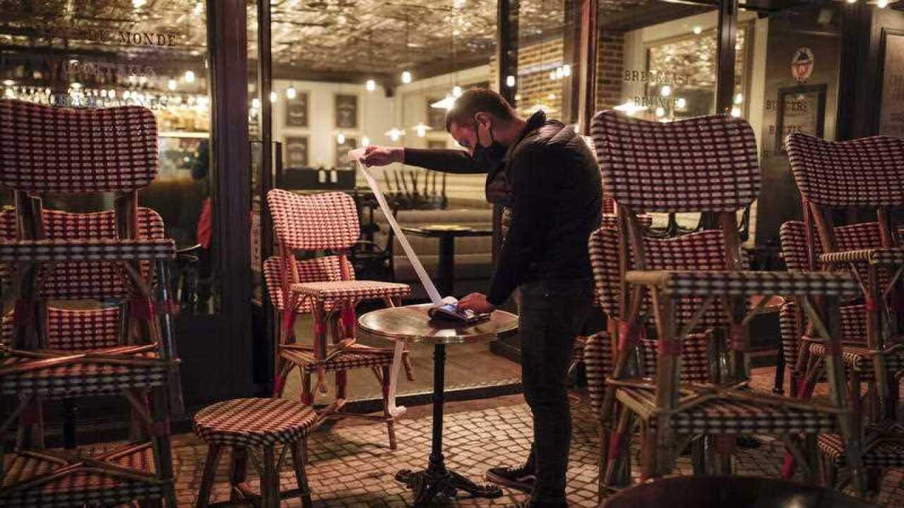 A waiter checks the final revenue as he closes a bar terrace in Paris on 17 October.