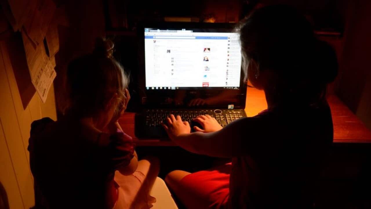 Young girls use a personal computer in Brisbane, Wednesday, Oct. 16, 2013. (AAP Image/Dan Peled) NO ARCHIVING