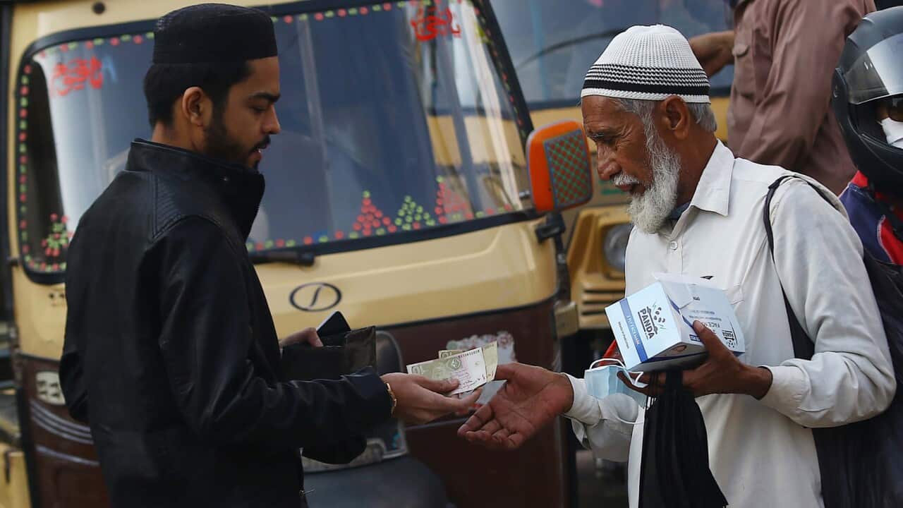 A man buys a face mask on a road, after new cases of COVID-19 were reported in Karachi, Pakistan.