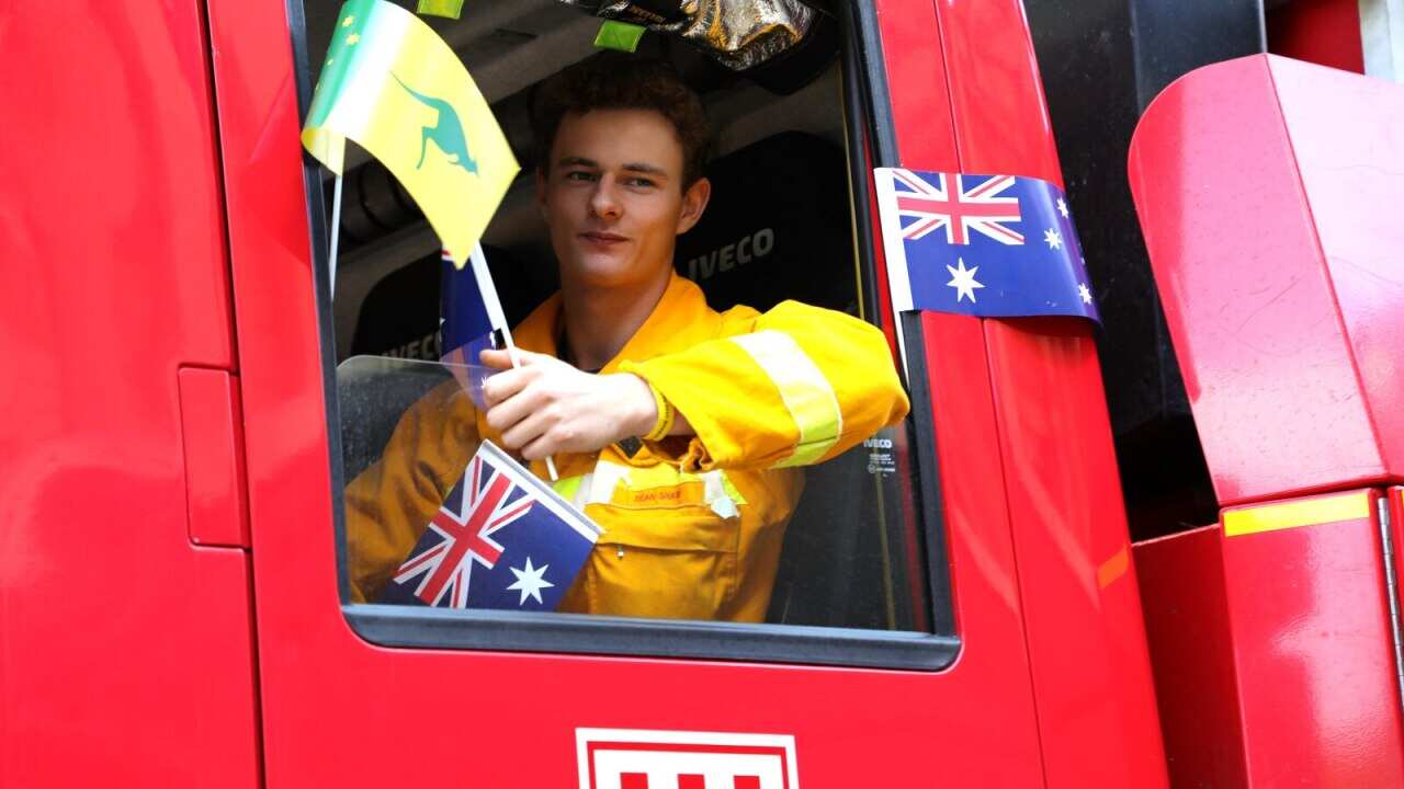 Rural firefighter Dean Shaw waves at the crowd as part of a contingent leading the Australia Day commemorations in Melbourne.