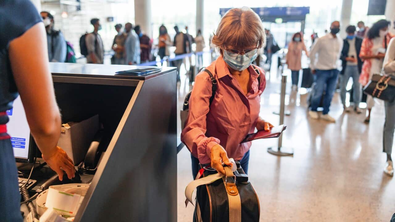 A Senior Woman Checking In Her Luggage At The Airport