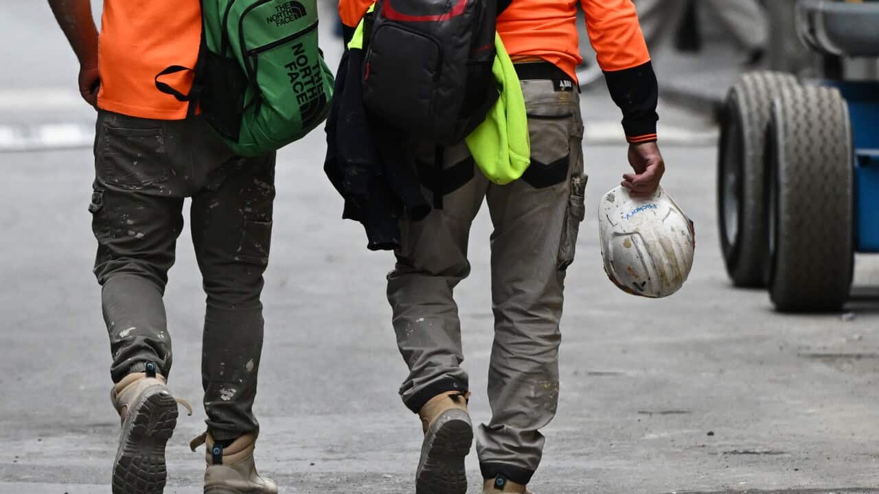 Two men wearing high-vis vests walk side-by-side