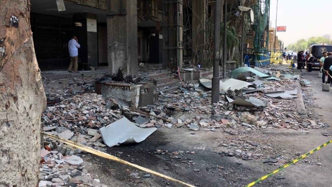 People walk in front of the damaged façade of the National Cancer Institute after an overnight fire from a blast, Cairo, Egypt