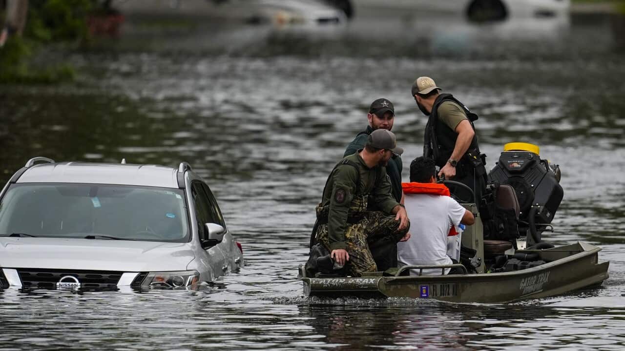 Rescued people sit in a boat through flooded streets.