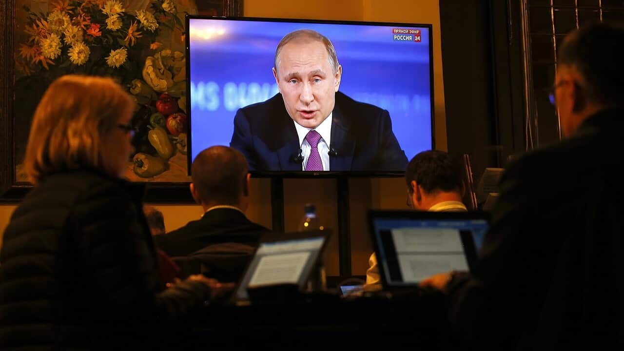 Journalists watch Russian President Vladimir Putin speaking on TV during his annual Question and Answer live broadcast