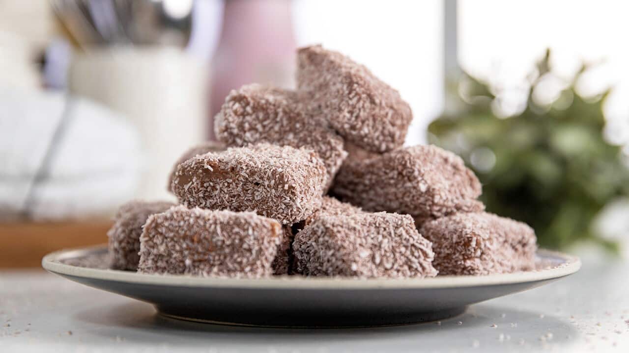 A low stack of chocolate coloured blocks, coated in coconute, sit on a plate.