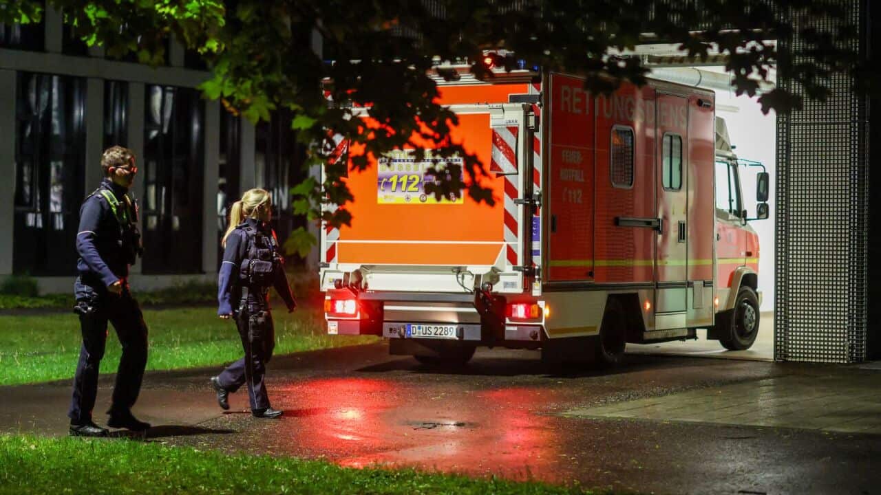 Police officers walk past an arriving ambulance taking a German patient to the infection center at Düsseldorf University Hospital, Wednesday, May 6, 2026, in Düsseldorf, Germany. (Christoph Reichwein-dpa via AP).jpg