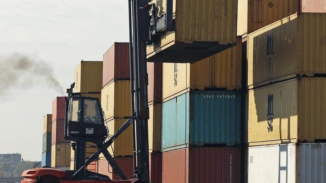 Shipping containers being stacked by a forklift