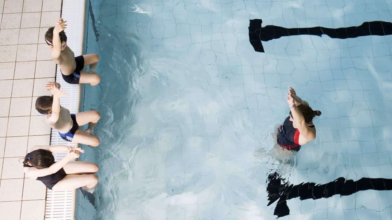 Swimming coach teaching children