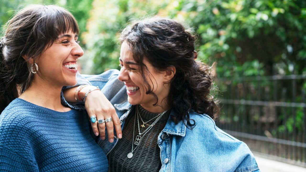 Woman smiling and leaning on her freinds shoulder