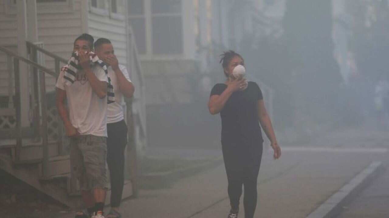 People cover their faces to protect themselves from heavy smoke from a fire in Lawrence, north of Boston.