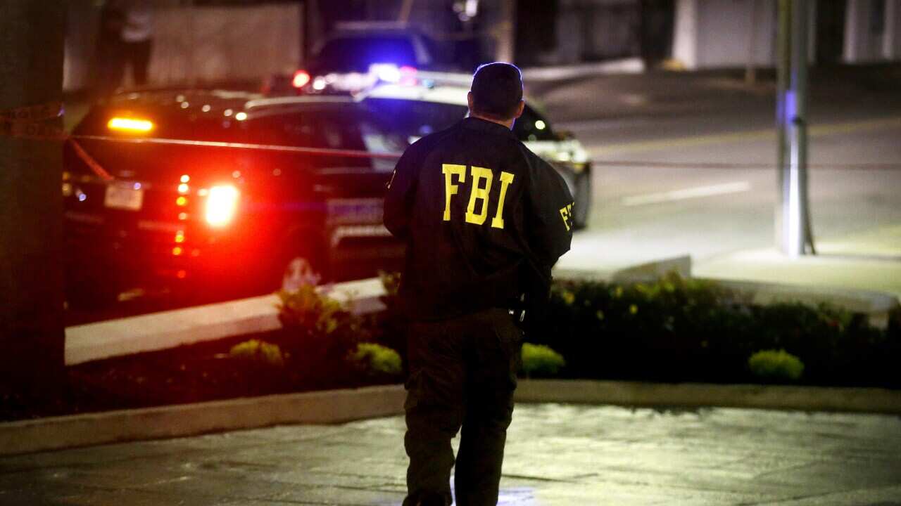 An FBI agent walks across the street from the Emanuel AME Church following a shooting Wednesday, June 17, 2015, in Charleston, S.C. (AP Photo/David Goldman)