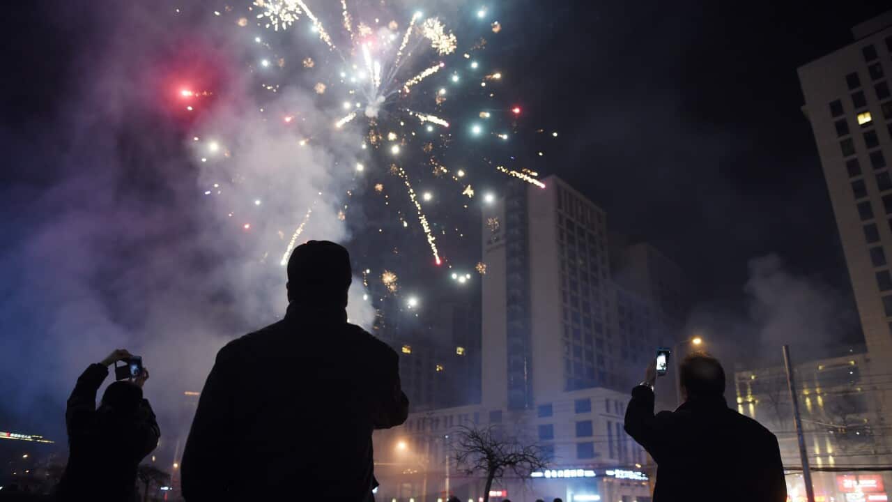 People photograph fireworks on a street in Beijing.