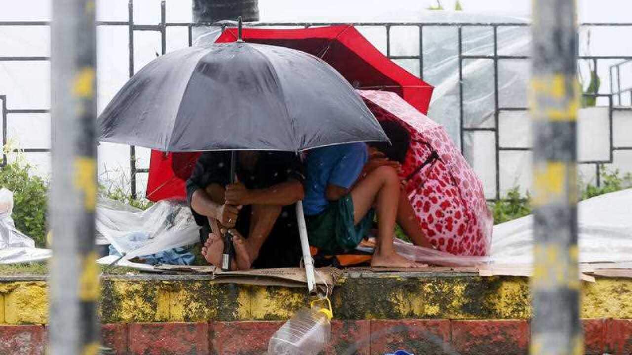 Residents huddle together under their umbrellas as strong winds and slight rain are brought by Typhoon Koppu Sunday, Oct. 18, 2015 in Manila, Philippines.