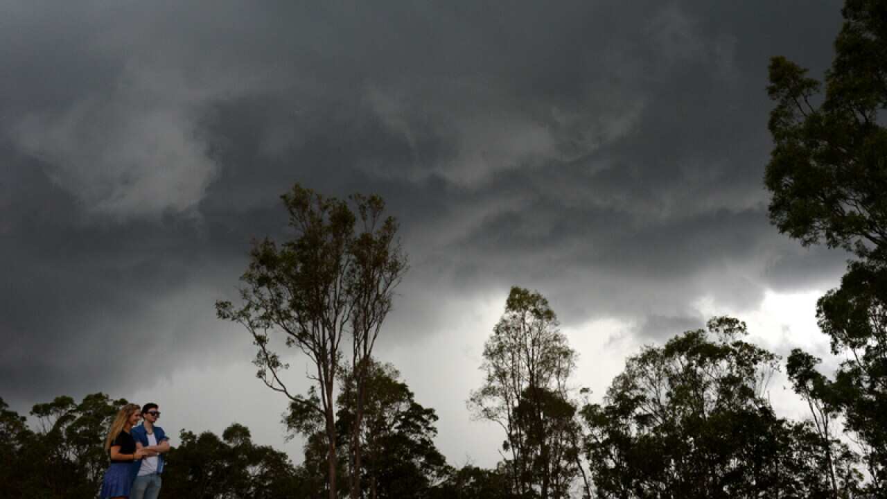 A couple watches storm clouds as they roll over Brisbane