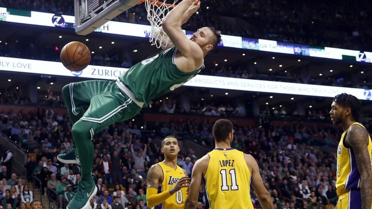 Boston Celtic's Aron Baynes hangs from the rim after dunking