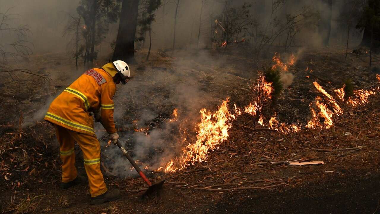 Rural Fire Service volunteers (RFS) and Fire and Rescue NSW officers (FRNSW) contain a small bushfire which closed the Princes Highway south of Ulladulla, Sunday, January 5, 2020.