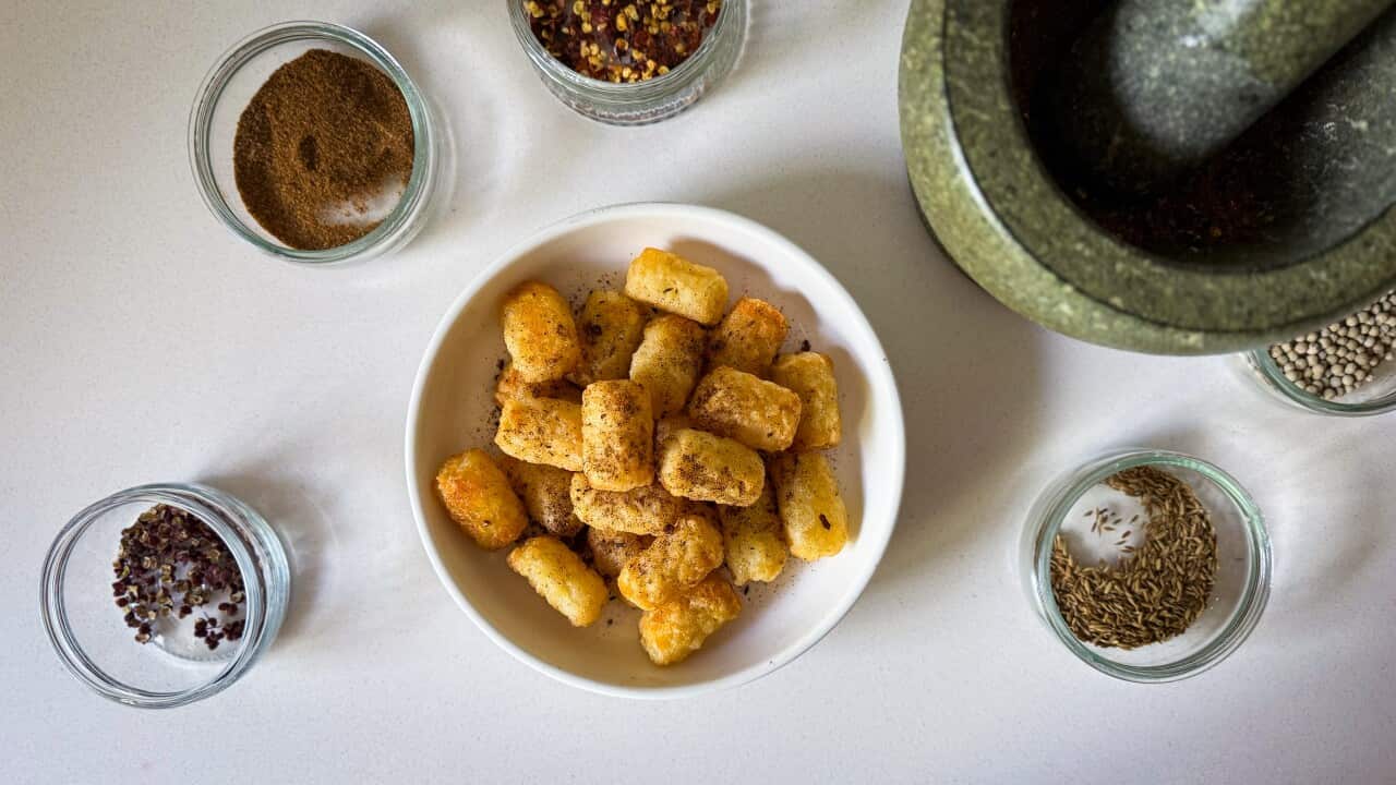 Plate of potato gems sprinkled with the spice mix. A mortar and pestle surrounded by the spices used sits to the side.