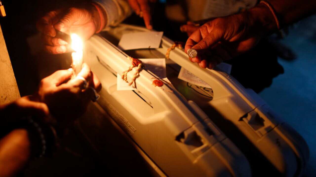 Election officers seal an electronic voting machine at the end of polling in Varanasi, India