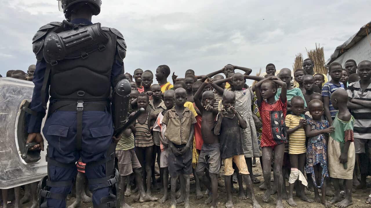 A crowd of displaced people in South Sudan look on as members of the U.N. multi-national police contingent provide security.