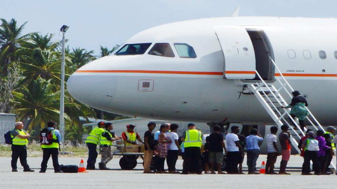 A group of asylum seekers board a plane at Cocos Island