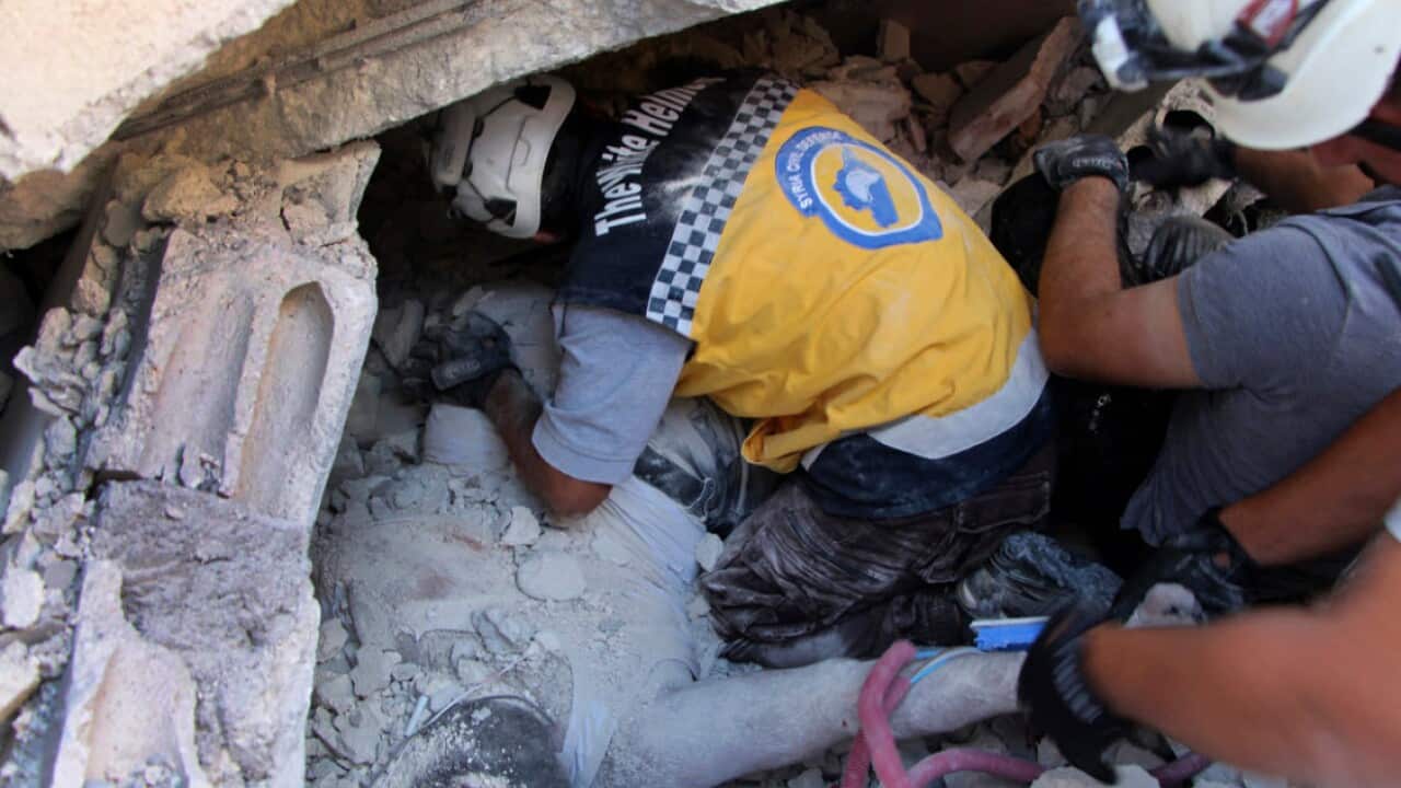 Syrian White Helmet workers remove a body from the rubble at the scene of an explosion in the village of Sarmada.