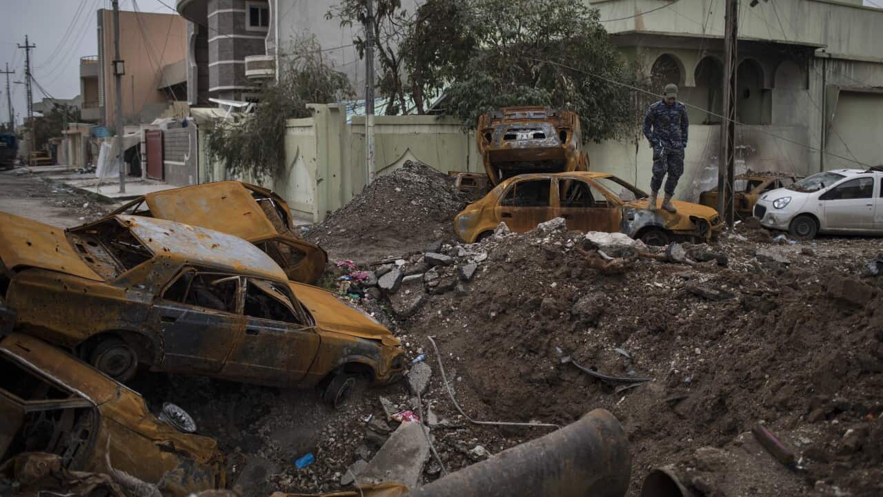 A policeman stands on top of a damaged car