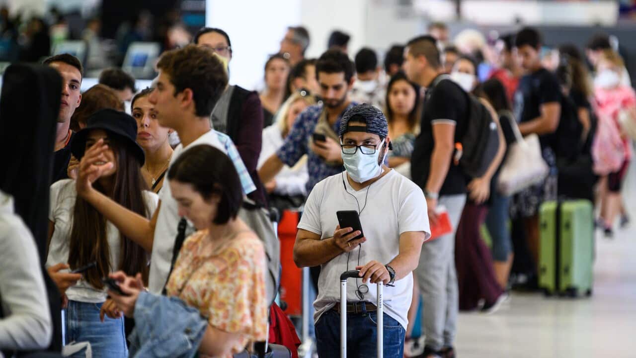 A long queue of passengers waiting to check in for a flight, including some passengers wearing protective face masks at Sydney International Airport, Friday, March 20, 2020. (AAP Image/James Gourley) NO ARCHIVING