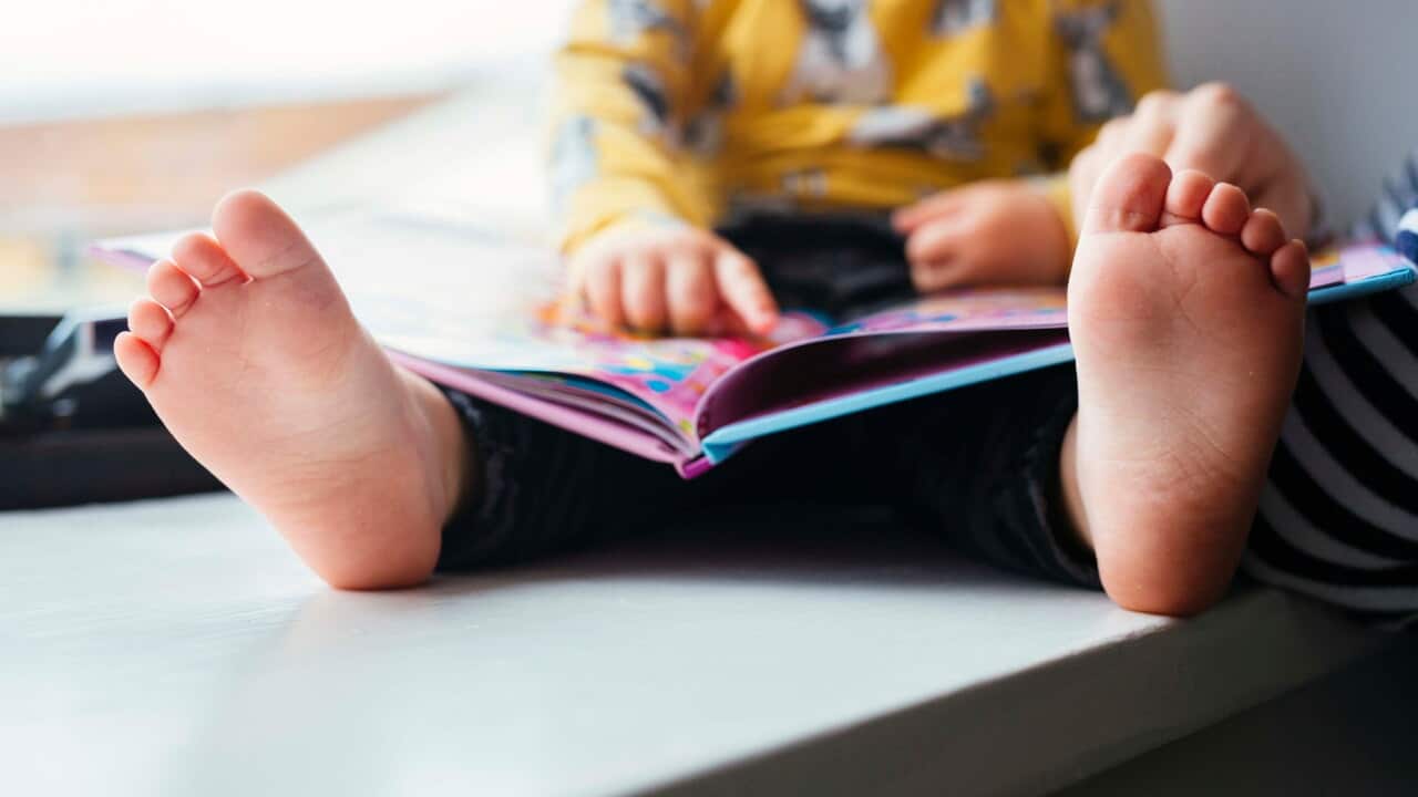 Cropped image of father and daughter with picture book at home