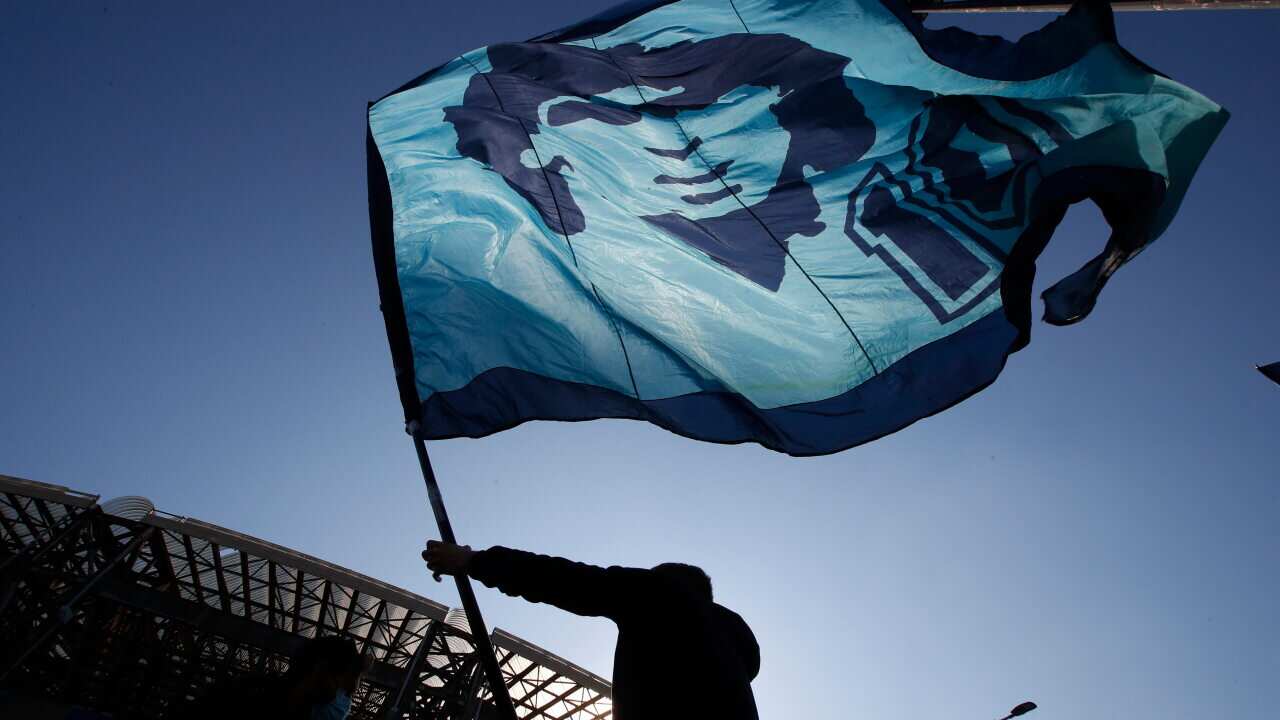 A man waves a flag commemorating soccer legend Diego Maradona outside the San Paolo stadium.