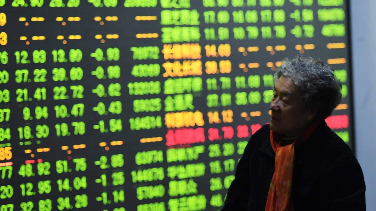 A woman walks past a screen in the brokerage house in Hangzhou, Zhejiang province, China.